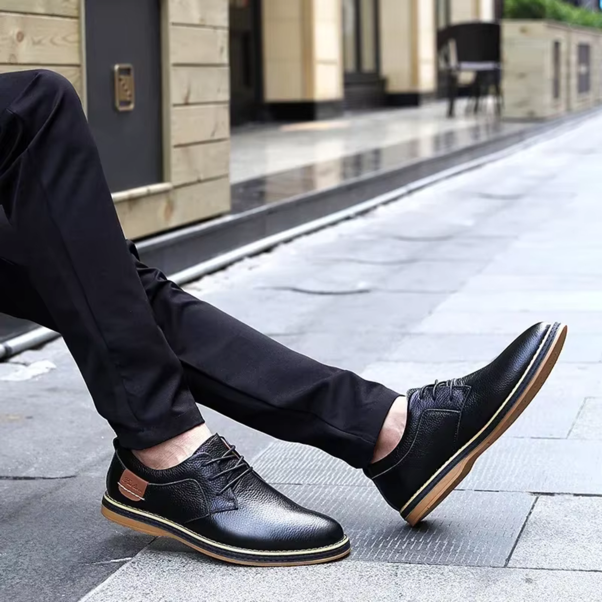 Black genuine leather men's moccasins with brown sole detailing, worn casually outdoors.